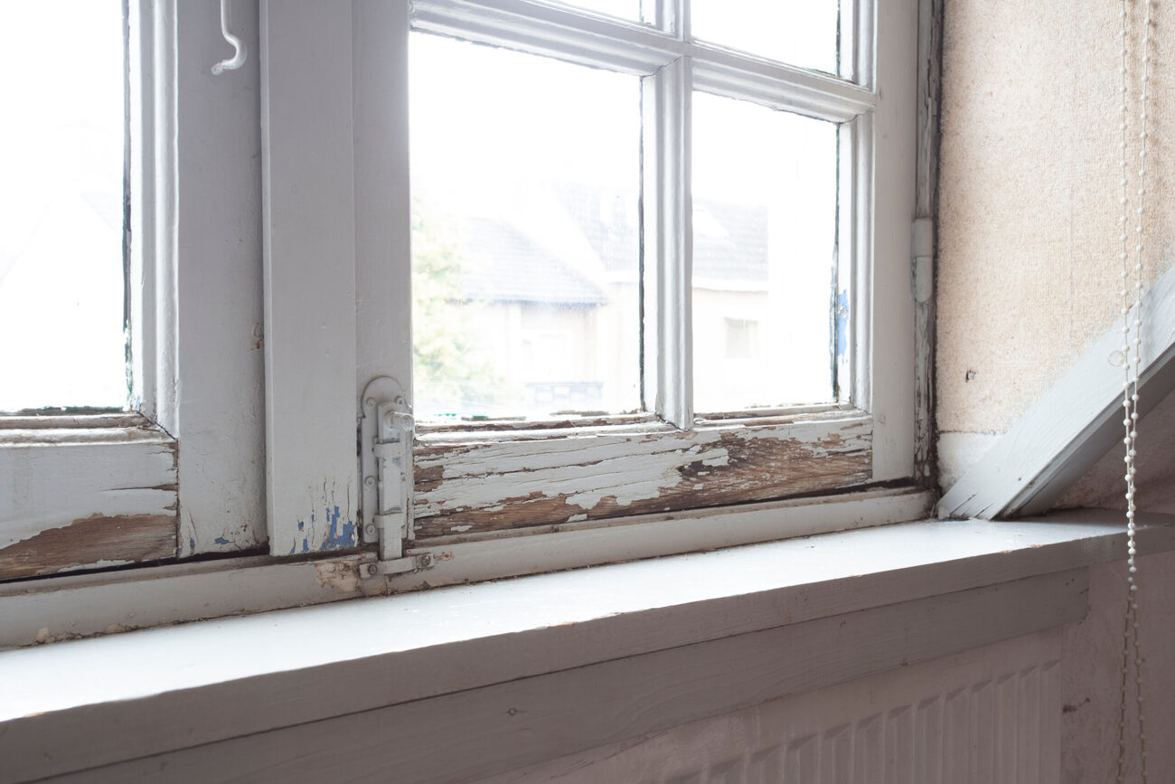 Old wooden window frames rotting and visibly damaged